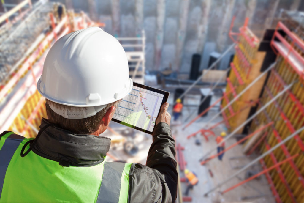 Male facility manager in a construction site using a tablet device to access FM software needed for managing his tasks.